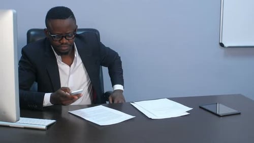 Man Checks Phone, Then Works at Office Computer