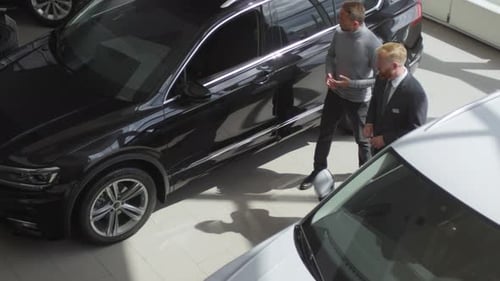 Top View of Car Dealer Talking with Man in Auto Showroom