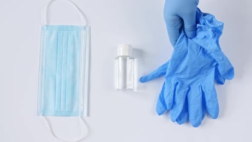 Gloved Hand Arranges Medical Supplies on White Surface
