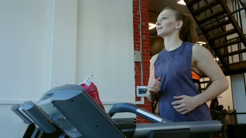 Woman Exercising on a Treadmill in a Gym