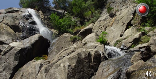 Waterfall Cascading Down Rocky Hillside on Sunny Day