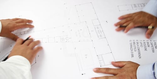 Architects Collaborate Over Building Blueprint in Office