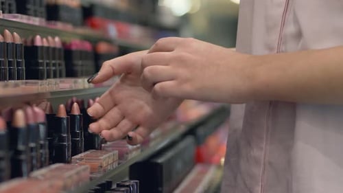 Stylish Female wählt dekorative Kosmetik für Lippen für lebendiges Make-up und wendet Lippenstifttests