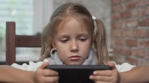 Young Girl Looks At Electronic Device