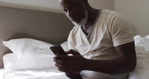 Man Using Phone While Sitting in Bed