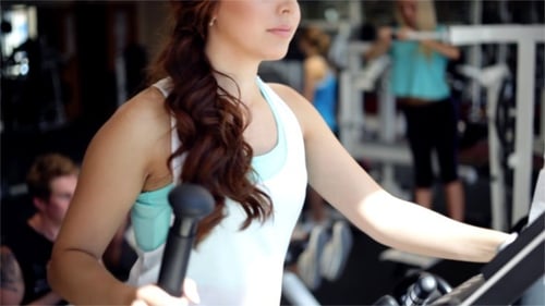 Woman Exercising on Elliptical Machine at Gym