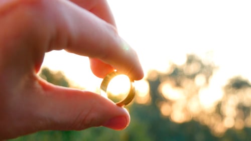 Golden Wedding Ring Held Up to Sunset Light