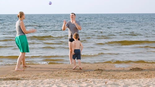 Padres e hijos jugando a la pelota en la playa