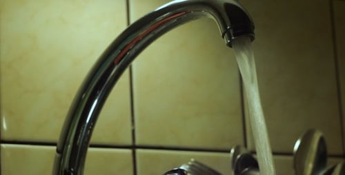 Water Flows From Faucet Into Stainless Steel Sink