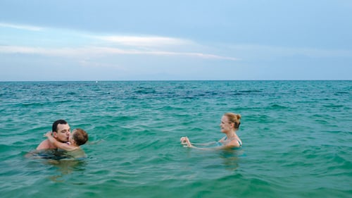 Boy In Sea Walking From Mother To Father