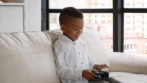 Happy Boy Playing Video Game on Sofa