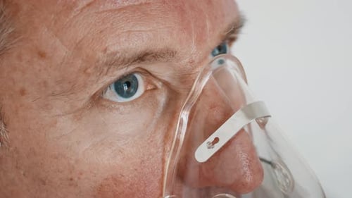 Homme âgé respirant à travers un masque inhalateur dans une clinique en gros plan
