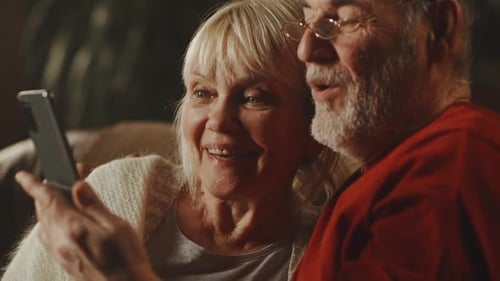 Senior Couple Using Mobile Phone Together Indoors