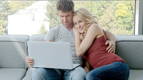 Affectionate Couple Relaxing at Home with Laptop