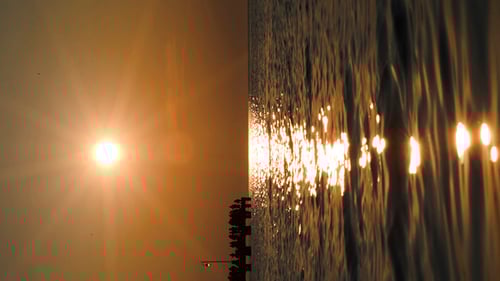 People On Pier In Distance At Sunset