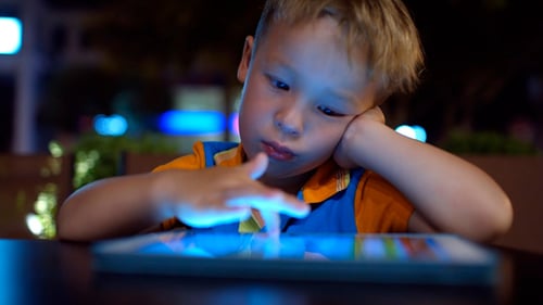 Bored Little Boy Using Pad In Cafe