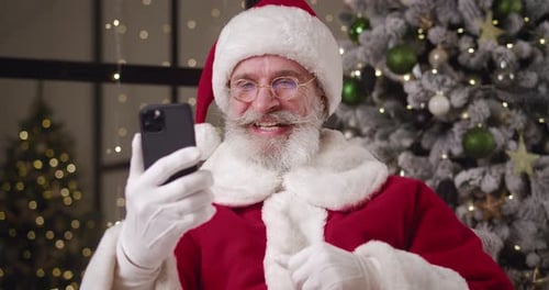 Kind Elderly Santa Claus Talking By Video Call Greeting His Interlocutor and Showing Thumb Up to
