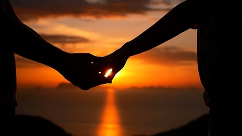 Couple Holds Hands at Beautiful Sunset Over Ocean