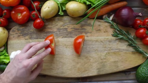 Male Hands Cutting Tomato into Two Halves