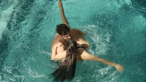 Pareja romántica abrazándose en la piscina cubierta. Hombre con mujer en brazos en piscina termal