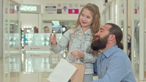 Little Girl Pointing Away, Showing Something To Her Father at the Shopping Mall