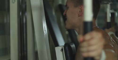Shirtless Man Uses Weight Machine in Gym