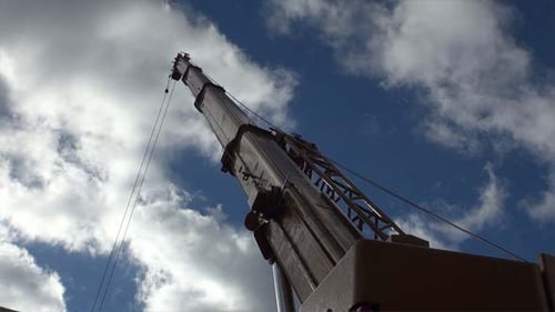 Crane Reaching High Against Blue Sky and Clouds
