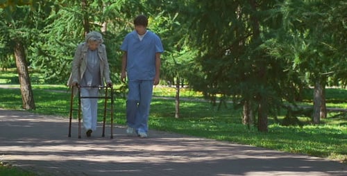 Elderly Woman Walking with Caregiver in Park