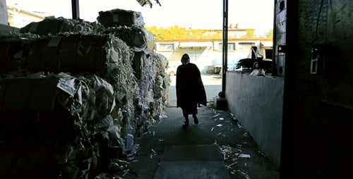 Adult Walks toward Light in Industrial Paper Recycling