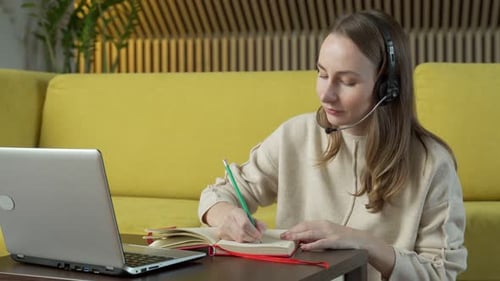 Woman Working At Home with Laptop and Notebook