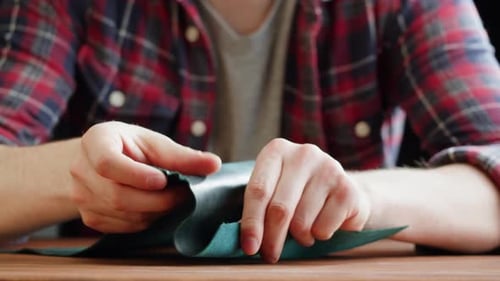 Adult Inspecting Piece of Green Leather