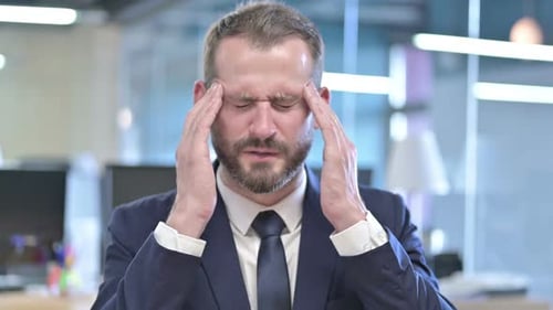 Portrait of Tired Businessman Having Headache in Office