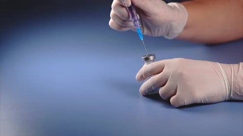 Mischen von Medikamenten. Doktor durchbohrt den Deckel der Ampulle
mit einer Spritze