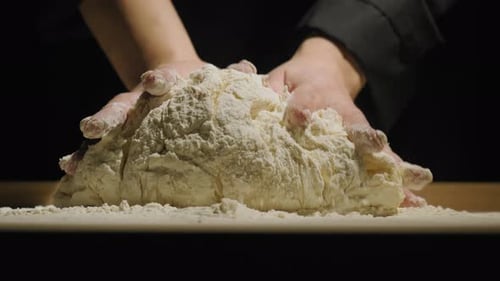 Hands of Baker kneten Teig einzeln auf schwarzem Hintergrund
