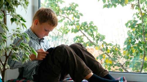 Boy Sits on Window Seat Using Mobile Phone