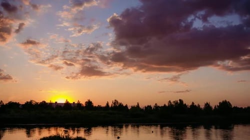 The Sun Sets Over the Horizon with the Forest Above the River. Summer Evening