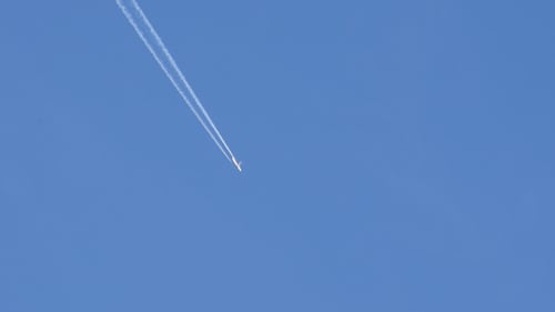Airplane Ascends Leaving Vapor Trail in Blue Sky