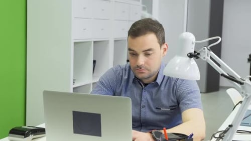 Focused business man entrepreneur typing on laptop doing research. Young male professional