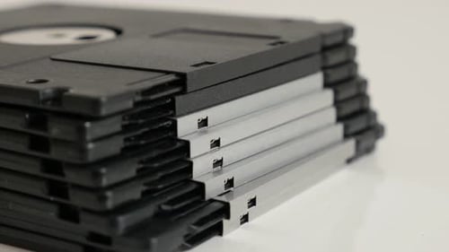 Classic magnetic floppy disc media on white slow tilt 4K 2160p 30fps UHD footage - Black data stora
