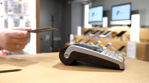 Closeup of Female Hand Paying Via Plastic Card with NFC Chip on Bank Terminal