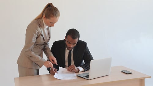 Business People Reviewing and Signing Documents in Office