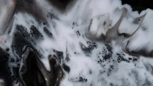 White Paint Spreads on a Black Goldglittering Moving Background