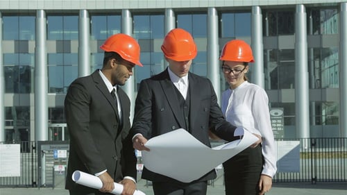Smiling Engineers Analyzing Blueprints at Construction Site
