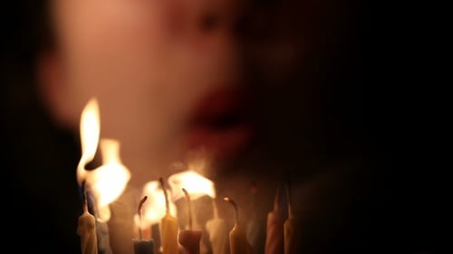 Happy Young Woman Blows out Birthday Candles
