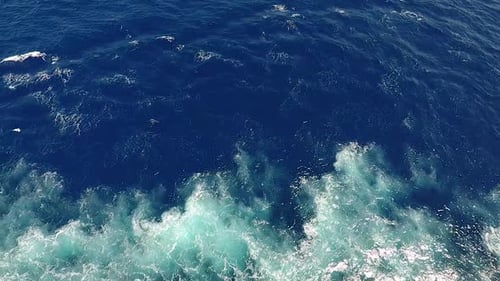 Vue de dessus sur les vagues, la mousse et les éclaboussures dans l'océan, journée ensoleillée.