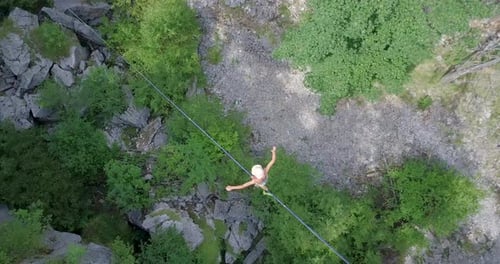 Woman Tightrope Walking Over Rocky Forest Terrain