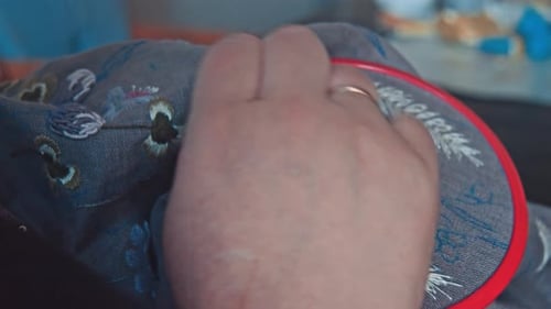 Hands Embroidering Floral Design onto Fabric Close Up