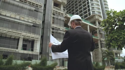Engineer Male Men Wearing Face Protective Mask Holding a Blueprint of the Building and Working