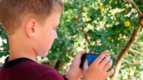 Boy Playing Game on Smartphone Outdoors