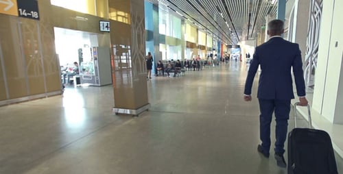 Man in Suit Pulls Rolling Suitcase in Airport